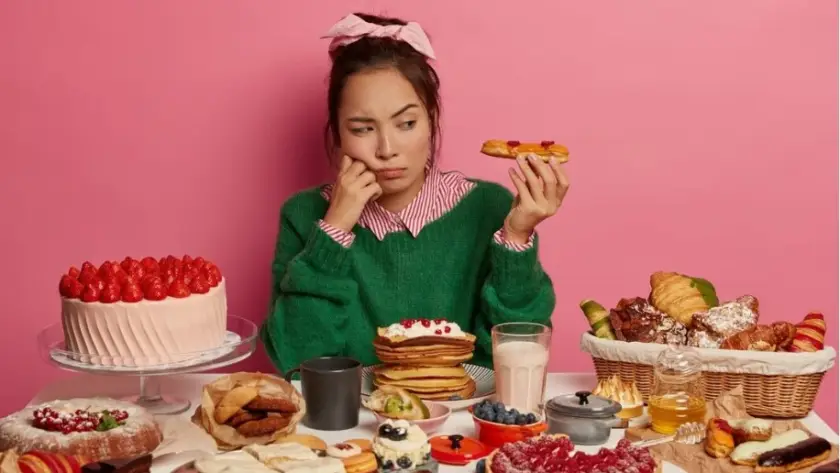 Common Challenges During Weight Loss Maintenance a woman sitting at a table with food.Binge-Eating_-Stress-Eating