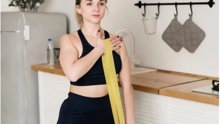 a woman in a black top and leggings holding a yellow band -Common-Challenges-and-Solutions-During-Weight-Loss-Maintenance