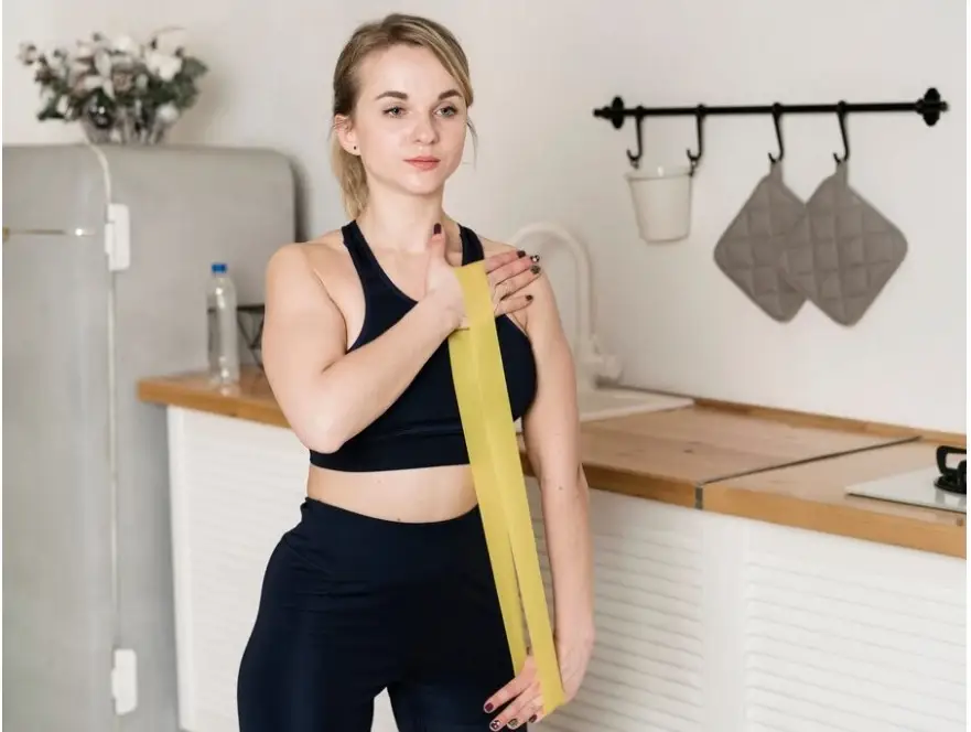 a woman in a black top and leggings holding a yellow band -Common-Challenges-and-Solutions-During-Weight-Loss-Maintenance