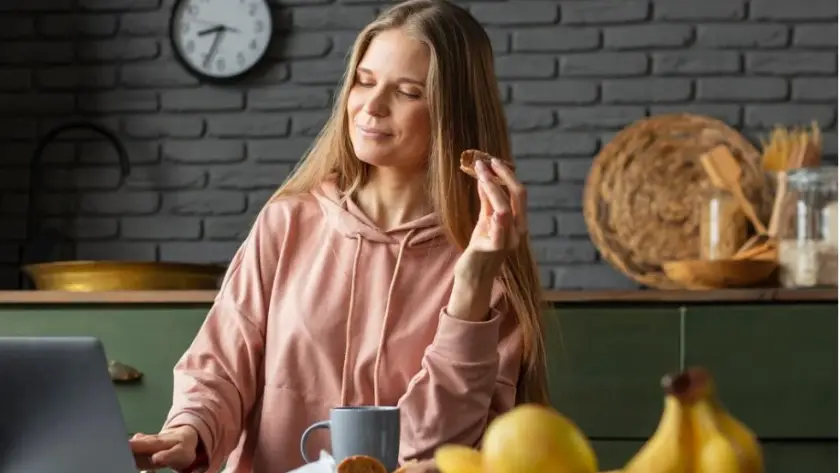 Common Challenges During Weight Loss Maintenance a woman holding a cookie in her hand.Common-Challenges-and-Solutions-During-Weight-Loss-Maintenance